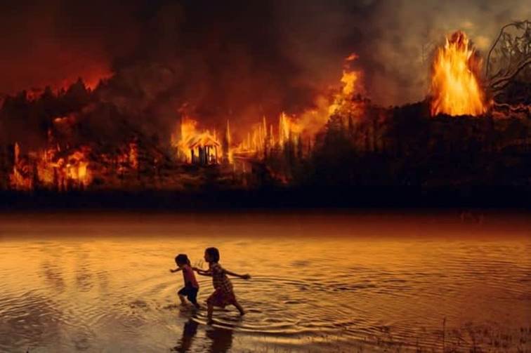 A couple of kids playing in the water with fire in the background

Description automatically generated with low confidence